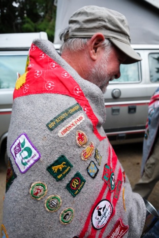 A man wearing a Scouts campfire blanket and badge collection.